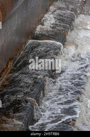 close-up of sea water rushing over a sea wall in an abstract surreal composition, water washing over stone wall, textures of water on stone, sea wall. Stock Photo