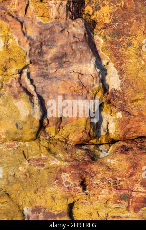 abstract rock formations in different colours on a cliff on the isle of wight, geology and patterns in rocks and cliffs with fissures and cracks. Stock Photo