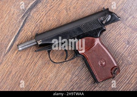 Top view of the old pistol of the Makarov system. Pistol on a wooden background. Close up. Stock Photo