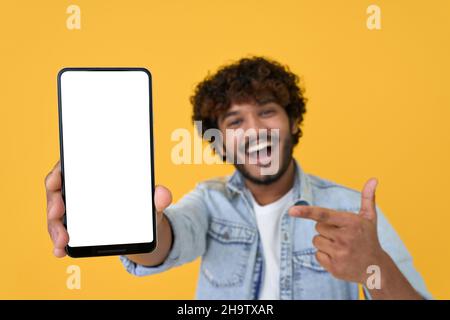 Happy young indian man showing big mockup phone screen on yellow background. Stock Photo