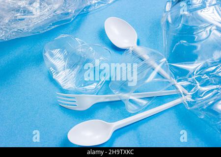 Plastic spoons, forks, bottles and cups as a disposable waste on bright blue background. Environmental pollution and litter recycling concept. Stock Photo