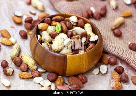 Different nuts: almonds, pistachios, peanuts, hazelnuts in wooden bowl on light background. Stock Photo