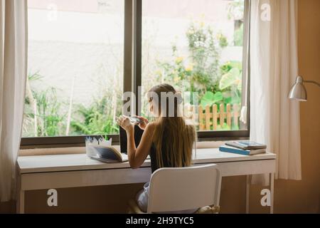 Young woman using mobile phone in her room. Stock Photo