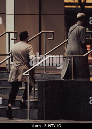 CALGARY, CANADA - Oct 31, 2021: The two busy working men in a rush walking up the stairs of a corporate building Stock Photo