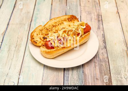 Brioche bread special hot dog with sausage, mustard grated cheese, ketchup and mayonnaise on white plate Stock Photo