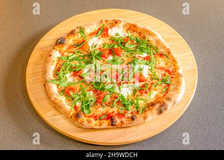 Pizza with burrata cheese, cherry tomatoes, arugula and serrano ham cooked in a stone oven Stock Photo