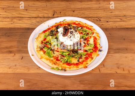 Pizza with burrata cheese, cherry tomatoes, arugula and serrano ham cooked in a stone oven Stock Photo