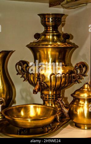A tea set made of ancient brass dishes, a beautiful samovar, a kettle, a bowl on legs, a water jug on a beautiful forged tray Stock Photo