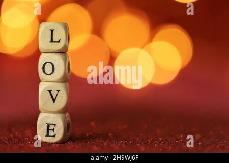 Love symbol .Valentine's Day. Inscription love made of letters on red glitter background with golden bokeh.Festive romantic background . Stock Photo