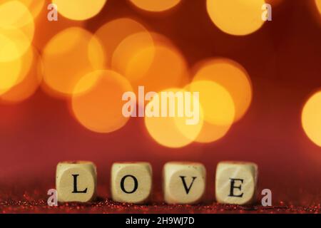 Love symbol .Valentine's Day. Inscription love made of letters on red glitter background with golden bokeh.Festive romantic background . Love and Stock Photo