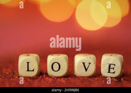 Love symbol .Valentine's Day. Inscription love made of letters on red glitter background with golden bokeh.Festive romantic background . Love and Stock Photo