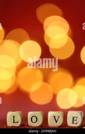 Love symbol .Valentine's Day. Inscription love made of letters on red glitter background with golden bokeh. romantic background . Love and Stock Photo