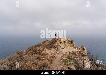 A lone tourist photographer stands on a mountain, against the backdrop of the ocean. Tenerife. Canary Islands. Spain. Stock Photo