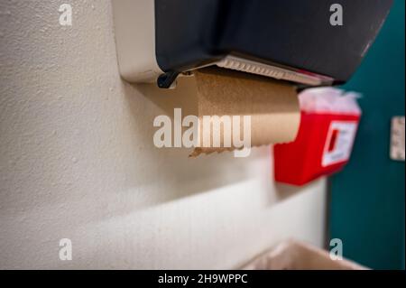 selective focus on a paper towel dispenser in a restroom used for drying hands after washing.  Stock Photo