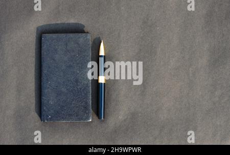 Pen placed on notebook on black background. High angle view. Copy space room for text. Stock Photo