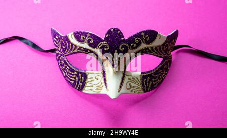 Carnival Venetian mask purple color with glitter on vibrant pink background. Traditional festival female disguise, masquerade Stock Photo