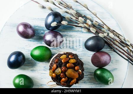 Easter cake with dried fruits and chocolate on a pastel background with colored eggs and willow twigs. top view Stock Photo