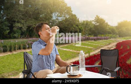 Senior man drinking water for keep cool in hot weather. Stock Photo