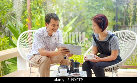 Middle aged couple relax sitting on chair in backyard patio. Stock Photo