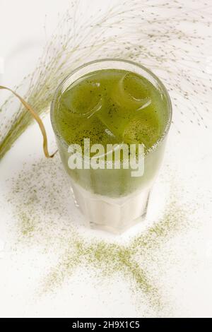 Matcha latte with coconut milk and ice in tall glass on white table Stock Photo