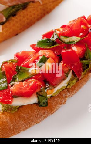 Closeup of bruschetta with tomato and basil salad, mozzarella and guacamole
