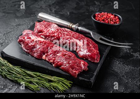 Raw Machete steak or hanging tender cut with herbs. Black background. Top view Stock Photo