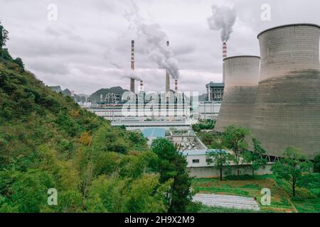 The cooling tower of the factory built next to the green space Stock Photo