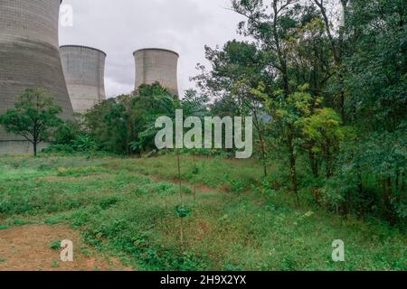 The cooling tower of the factory built next to the green space Stock Photo