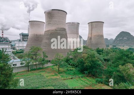 The cooling tower of the factory built next to the green space Stock Photo