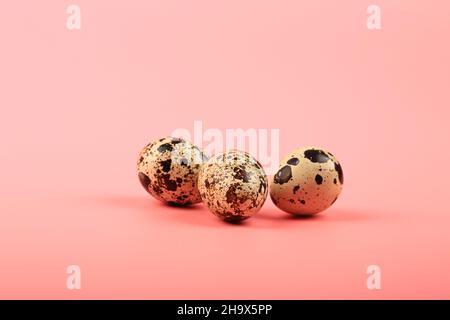 three quail eggs on a pink background Stock Photo