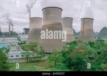 The cooling tower of the factory built next to the green space Stock Photo