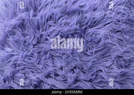 Purple soft fur for background or texture. Fluffy blue fur blanket. The color of 2022 very peri. Flat lay, top view, copy space. Stock Photo
