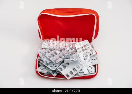 Side effects of pills and medication. Many used empty pills pack and medications blisters in red first aid kit on white background Stock Photo