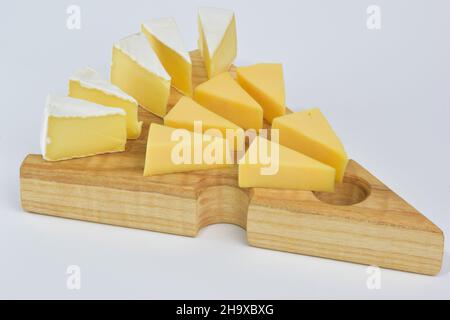 Several pieces of different types of cheese lie on a special wooden stand for cheese on a white clipping background Stock Photo