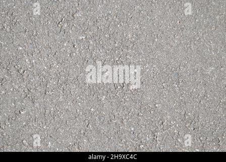 The texture of the asphalt on the road in a light shade illuminated by the sun for the whole frame, gray and grungy Stock Photo