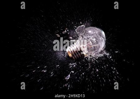 moment of impact explosion of a traditional light bulb on a black background. Stock Photo
