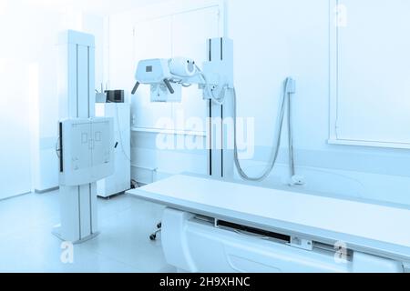 X-ray department in modern hospital. Radiology room with scan machine with empty bed. Technician adjusting an x-ray machine. Scanning chest, heart Stock Photo