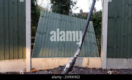 Broken fence panel with bent lamp post in the foreground Stock Photo