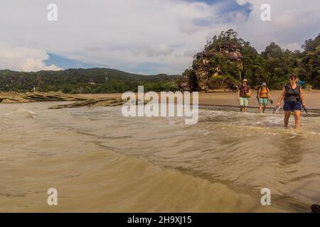 BAKO, MALAYSIA - MARCH 6, 2018: Tourists are wading to a boat in Bako national park on Borneo island, Malaysia Stock Photo