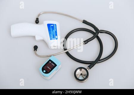 Stethoscope, pulse oximeter and thermometer gun on white background. Treatment of cold or flu. Phonendoscope. Infrared isometric thermometer gun to Stock Photo