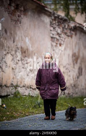 VILNIUS, LITHUANIA - OCTOBER 6 2021: Grandmother walking her dog in the old town Stock Photo