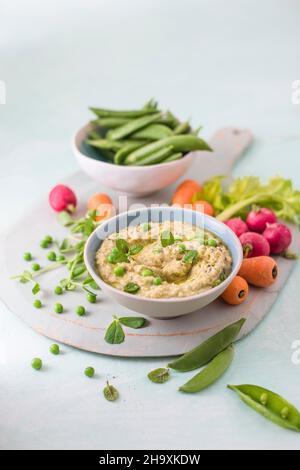 Houmous made of chickpeas, peas with mint and tahini, fresh vrgetables foe dipping on a side Stock Photo
