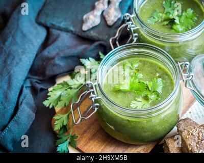 Vegan cream of baked zucchini, sweet potato and spinach soup served in mason jars Stock Photo
