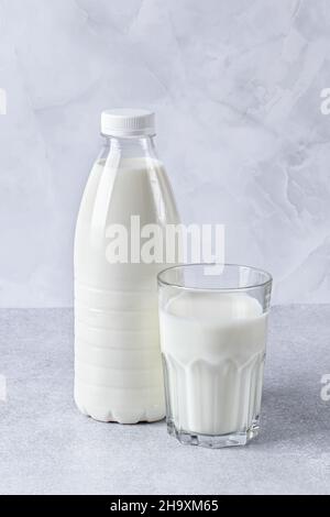 Full bottle and glass of milk on a gray table background. Healthy food, a source of calcium. Cooking ingredient, drink Stock Photo
