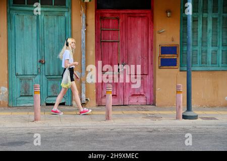 Young teenage woman walking along street of old city, vintage doors background Stock Photo