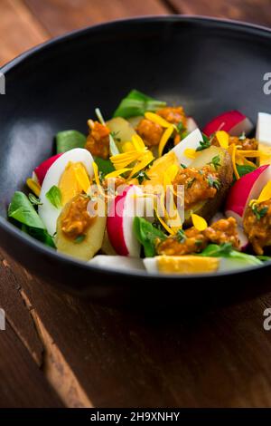 New potatoes with egg, radishes, lamb's lettuce, pesto and marigold flowers Stock Photo