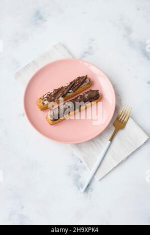 Two eclairs on a pink plate Stock Photo