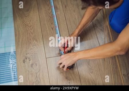 Man installing new wooden laminate flooring on a warm film floor. Infrared floor heating system under laminate floor Stock Photo