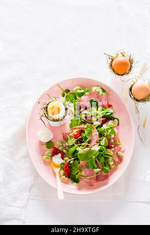 Salad with fava beans, dried tomatoes, ham and soft-boiled eggs Stock Photo