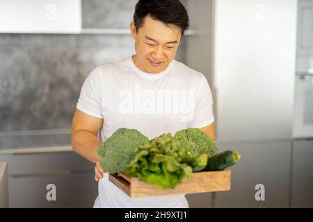 Man sniff fresh organic vegetables in wooden box Stock Photo